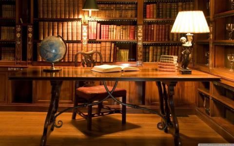Image of a desk, lamp and bookshelves in a room. 