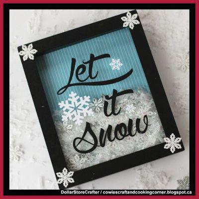 Image of a shadow box with lettering cut out that reads "Let it Snow" There are 4 snowflakes glued to the corners of the box