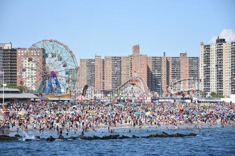 Image of Coney Island beach and amusement park on a busy summer day. 