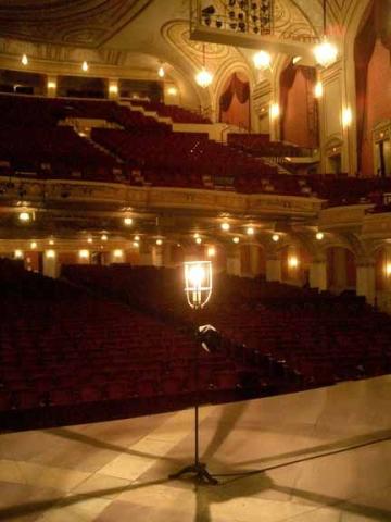 Photo of a Broadway Theater Auditorium. Red seats, gold walls and bright lights.