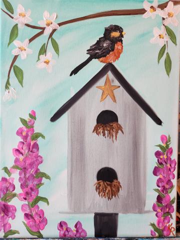 Canvas painting featuring spring flowers and a bird house with a Robin sitting on the roof of the bird house\.