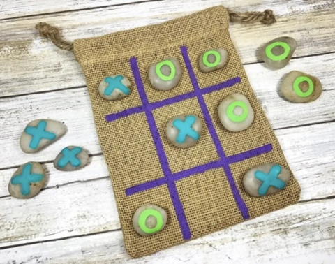 Tik Tac Toe board on a small satchel with rocks painted with blue X's and green O's