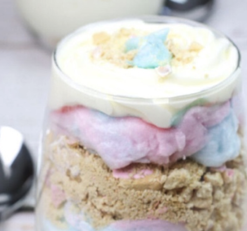 Cotton candy cheesecake jar, which is clear glass filled with pink and blue cotton candy and a white creamy topping.