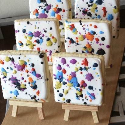 6 Cookies that are on little easels with "paint splatter" ice cream on the cookie canvasses. 