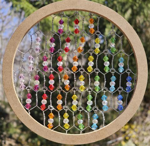 Image of the craft featuring a suncatcher made of a wring with chicken wire and crystals. 