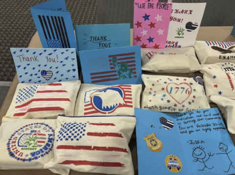 First responder kits, some with the American flag painted on them, others are blue, all are placed neatly on a table.
