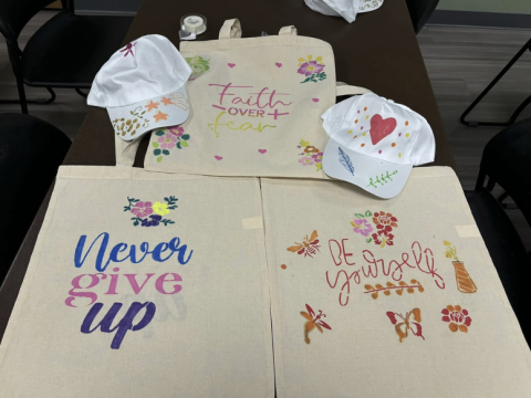 Tote bags with optimistic phrases painted on them such as never give up.