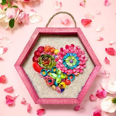 Image of the craft featuring a small frame with sand as the background and painted seashells forming colorful flowers.