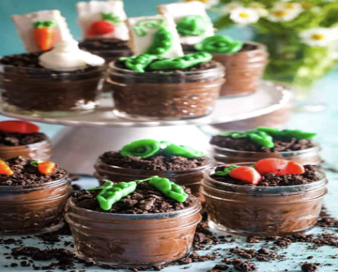 Dirt Cakes with green frosting and orange frosting as vegetables in a chocolate pot.