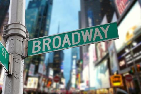 Photo of a street sign in NYC that says Broadway and building images blurred in the background.
