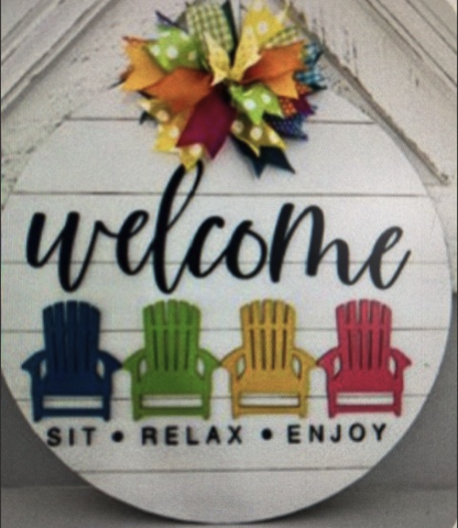 Image of the craft featuring a round wooden board with colorful chairs and bow and says welcome. 