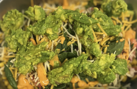 Close up of a Chipotle bowl with guacamole, cheese, rice, etc.