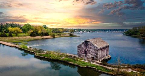 Image of an old wood structure on a strip of land with water on both sides.