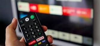 Person holding a television remote control pointing it at a television.