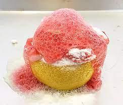 Image of a science experiment with a half of lemon with baking soda and vinegar causing foam.
