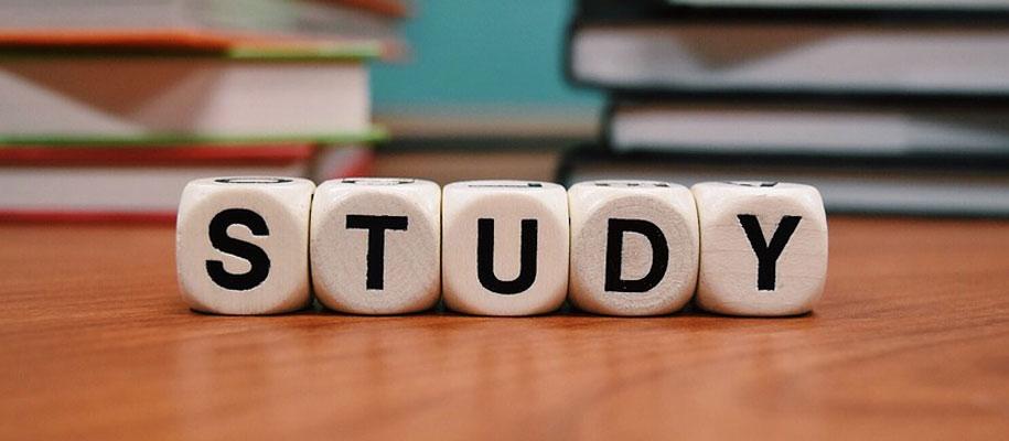 The word study spelled out on word dice. Books laying flat on the desk behind. 