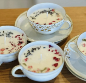4 Teacup Candles on sauces on a wooden table.