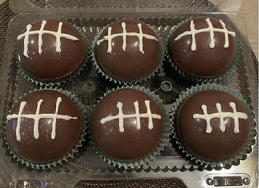 6 football shaped cocoa bombs in a baking tin.